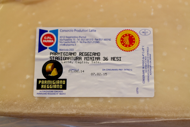 Notable markings are the black "Parmigiano-Reggiano" stamp on the bottom left and the yellow and red "Denominazione d'Origine Protteta" in the upper right corner