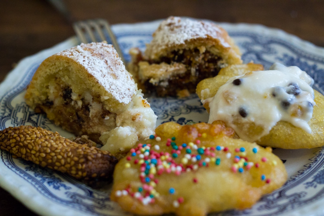 Biscotti regina (left- shortbread biscuits rolled in sesame seeds), cassata (back left- the homemade version which is a tart filled with sweetened ricotta with chocolate and candied fruit), buccelata (centre back- a pastry ring cake of Arab origin filled with chopped nuts, dried fruit and honey), sfinci del San Giuseppe (right and centre- feather light doughnuts served with honey, sugar and hundreds and thousands or filled with sweetened ricotta cream) 