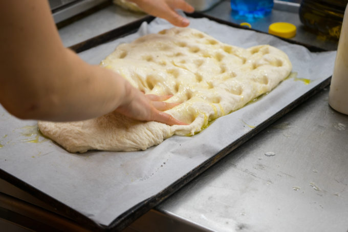 Dimpling the dough for focaccia at Bitega du Pan